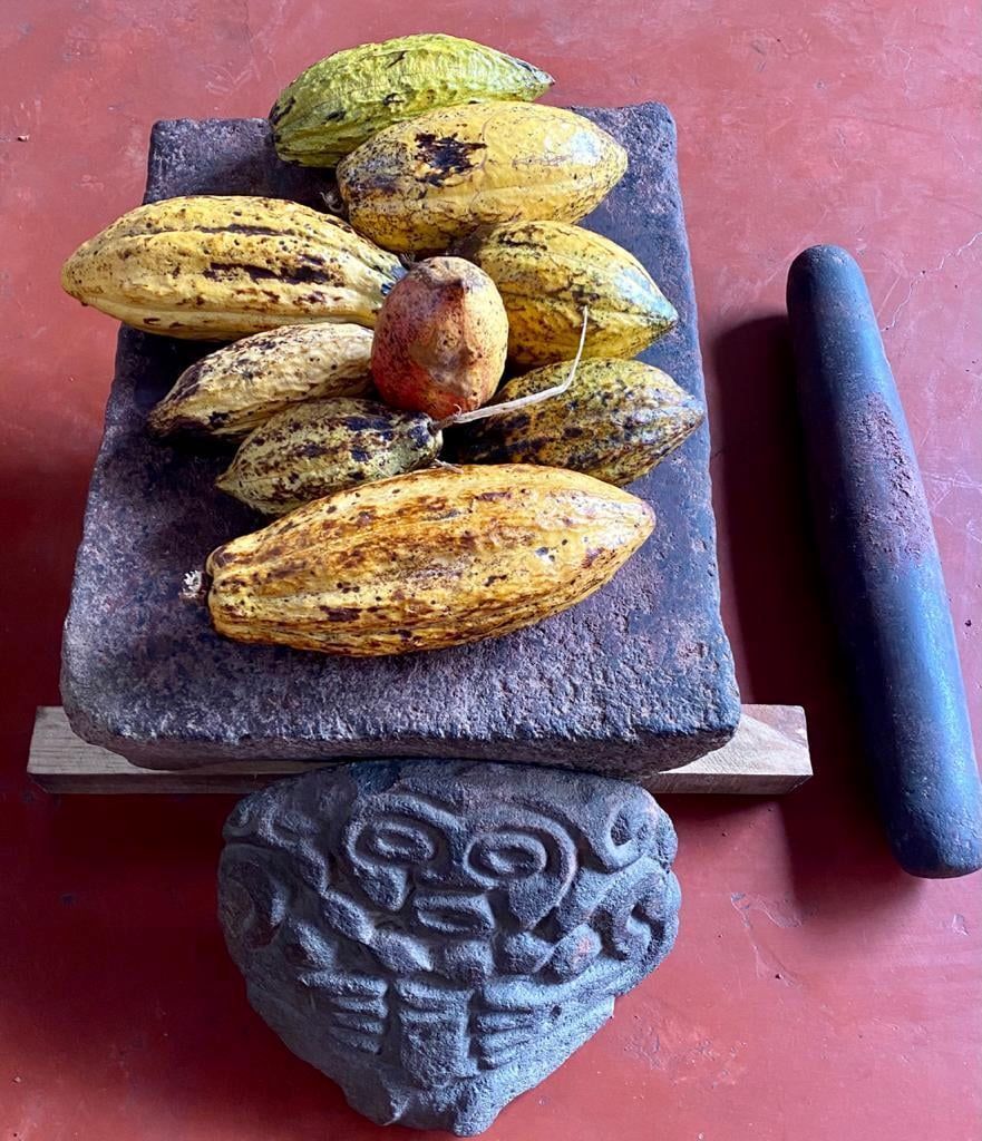 Ancient-style stone cacao grinder with fresh cacao pods in Guatemala