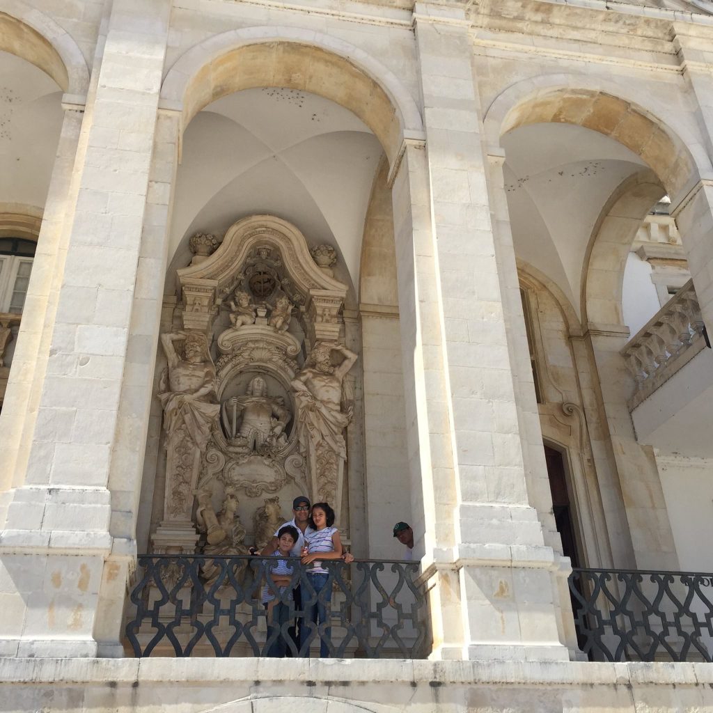  Father and two young children on the Baroque staircase of the University of Coimbra Portugal stone arches family travel