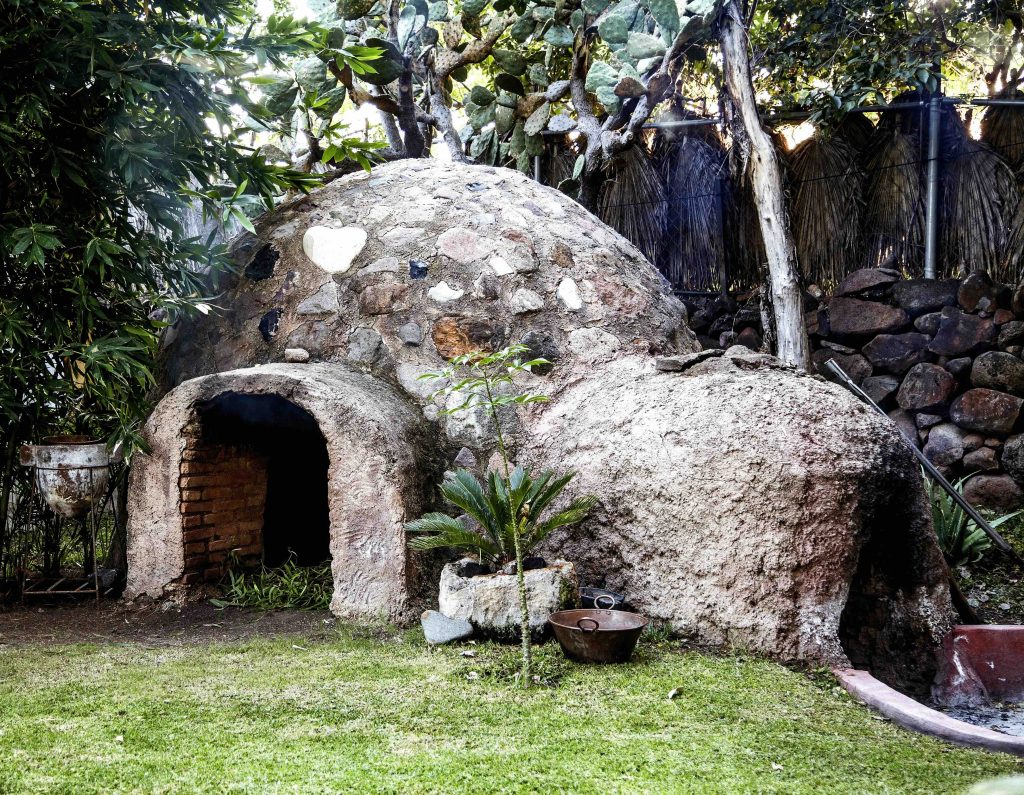 Traditional Mayan temazcal sweat lodge surrounded by tropical plants in Guatemala