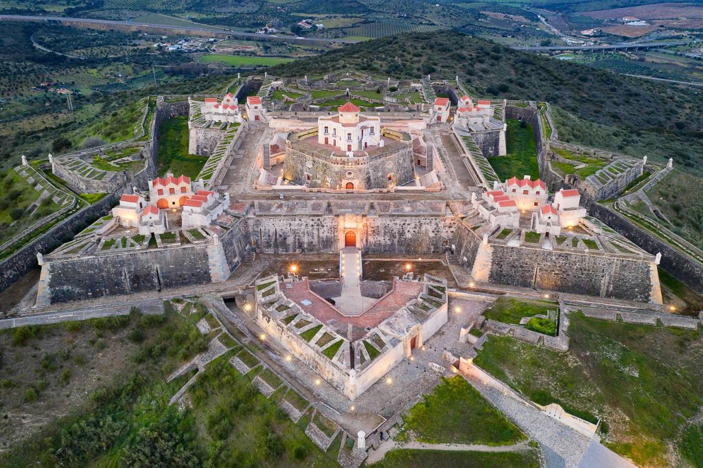 Aerial drone view of the star-shaped UNESCO fortifications of Elvas Portugal at dusk with lit bastions and green countryside surrounding