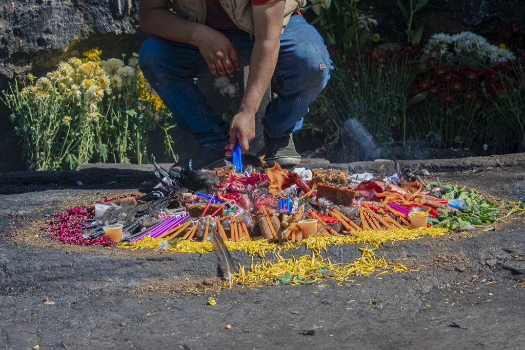 Indigenous healer performing a Mayan fire ceremony with candles and offerings in Guatemala