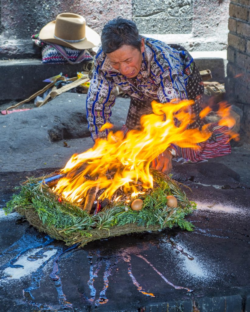 Mayan spiritual guide tending sacred ceremonial fire during a traditional Guatemalan ritual