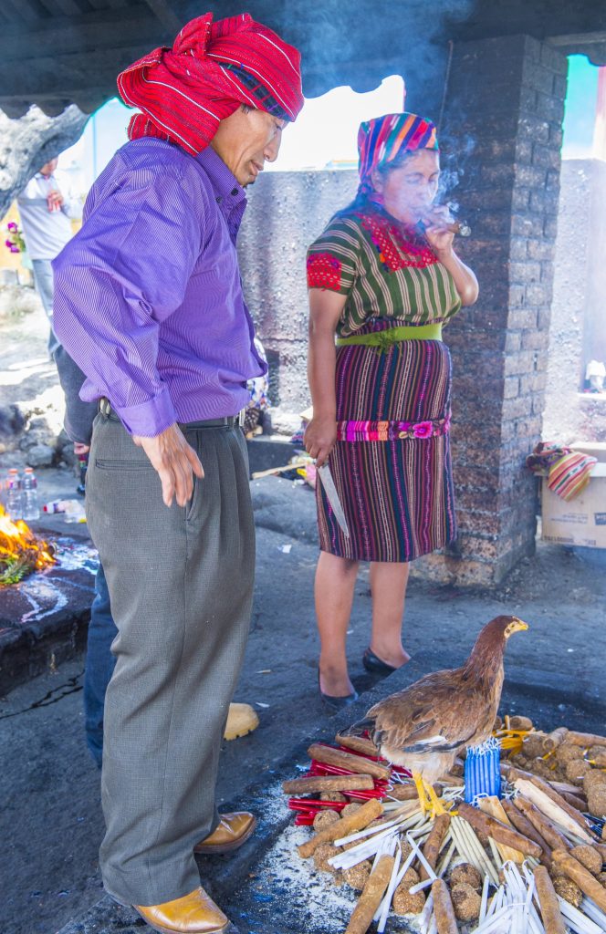 Mayan spiritual guide tending sacred ceremonial fire during a traditional Guatemalan ritual