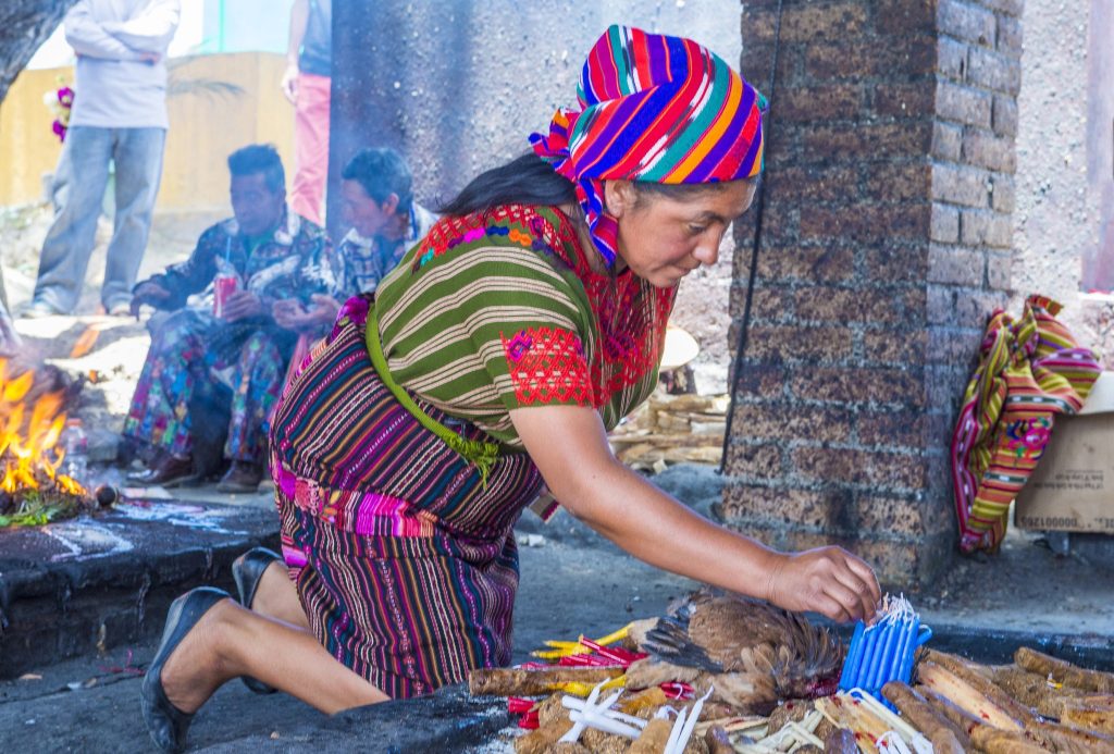 Mayan spiritual guide tending sacred ceremonial fire during a traditional Guatemalan ritual