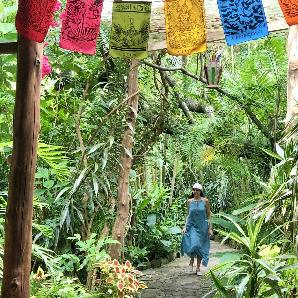 Woman walking beneath colorful prayer flags on a jungle path in San Marcos La Laguna Guatemala