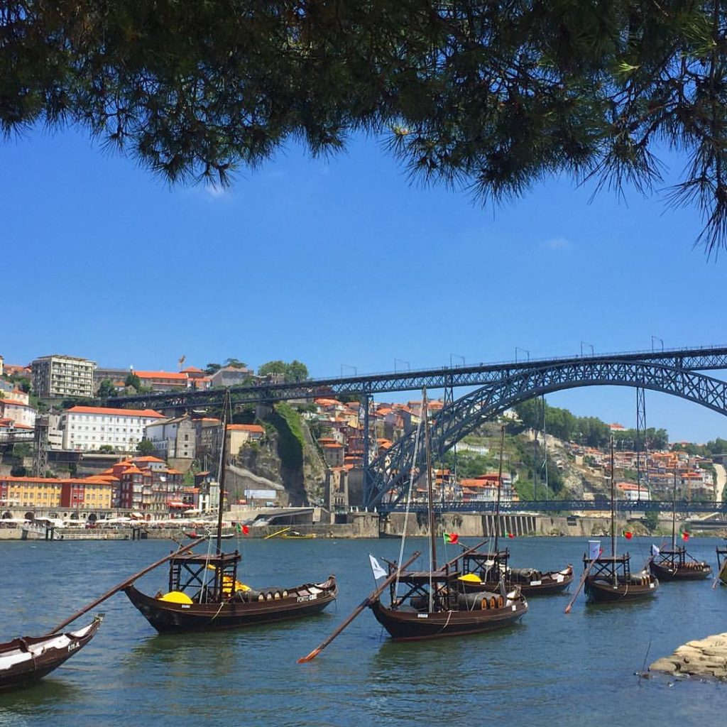 Traditional rabelo port wine boats on the Douro River in Porto Portugal with Dom Luis I bridge and Ribeira waterfront