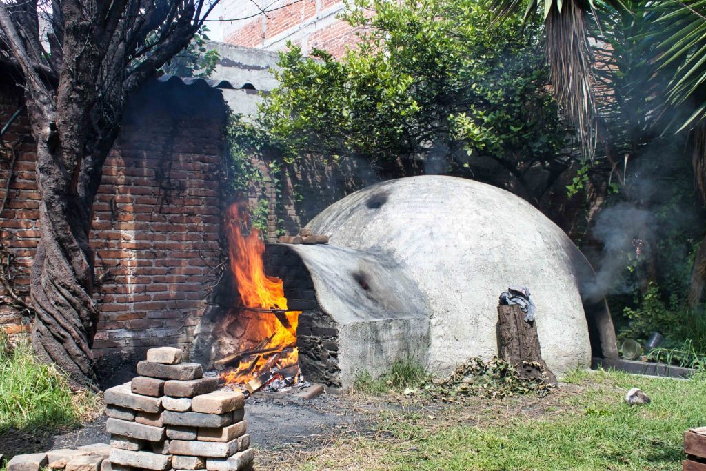 Traditional outdoor temazcal sweat lodge being heated with fire in Guatemala