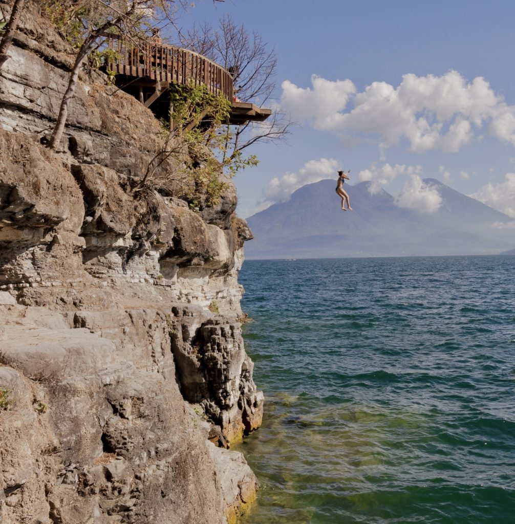 Person cliff jumping into Lake Atitlán in San Marcos La Laguna with volcano views in Guatemala
