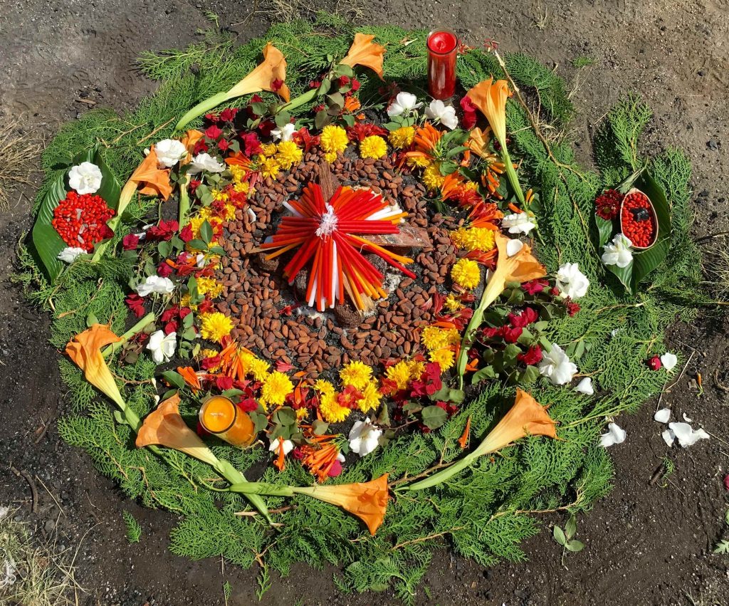 Traditional Mayan ceremonial altar with flowers, candles, cacao, and sacred offerings arranged in a circle