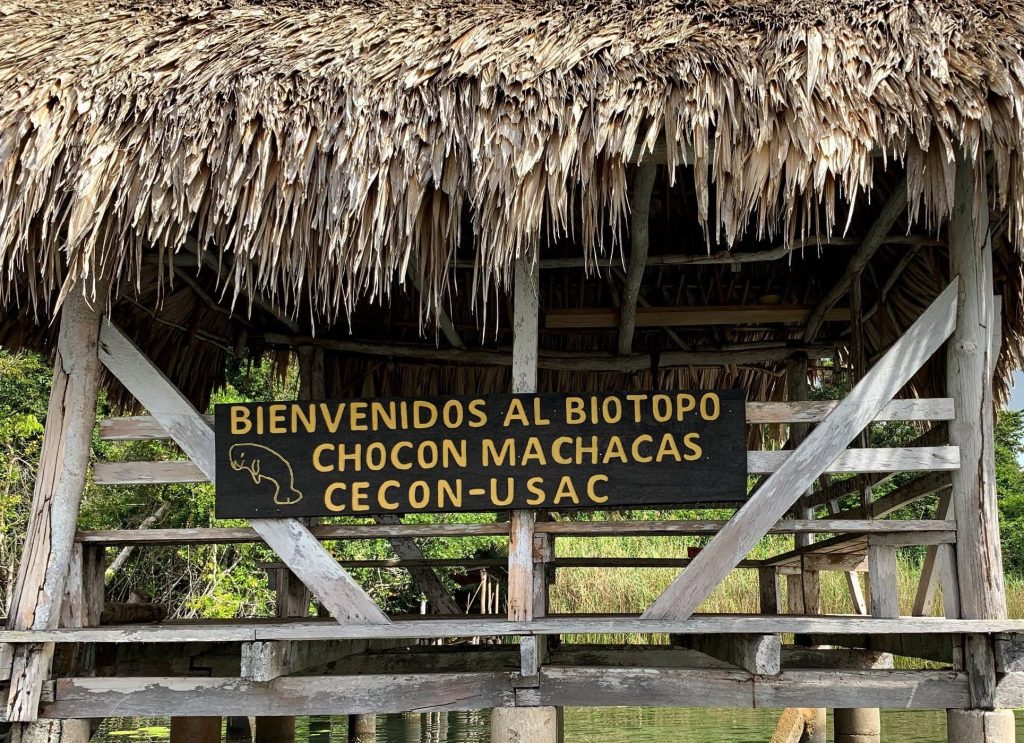 Sign for Biotopo Chocón Machacas CECON USAC at a thatched wooden dock in Río Dulce Guatemala.