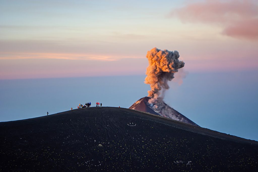 Hikers crossing barren volcanic terrain on the trail toward Fuego volcano