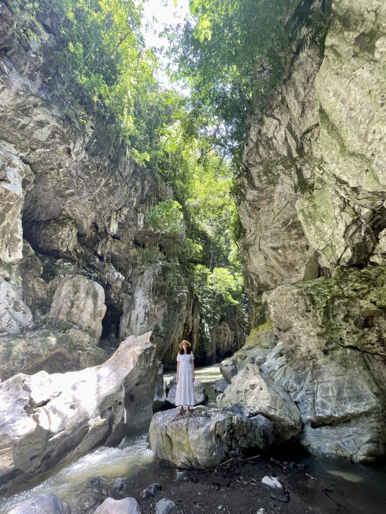 Woman standing on a rock inside the El Boquerón limestone canyon near Lake Izabal, Guatemala