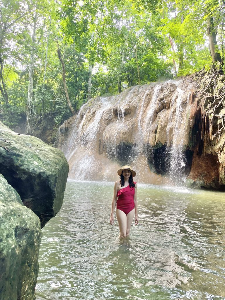 Traveler standing in the water below the hot spring waterfall at Finca El Paraíso near Lake Izabal Guatemala.