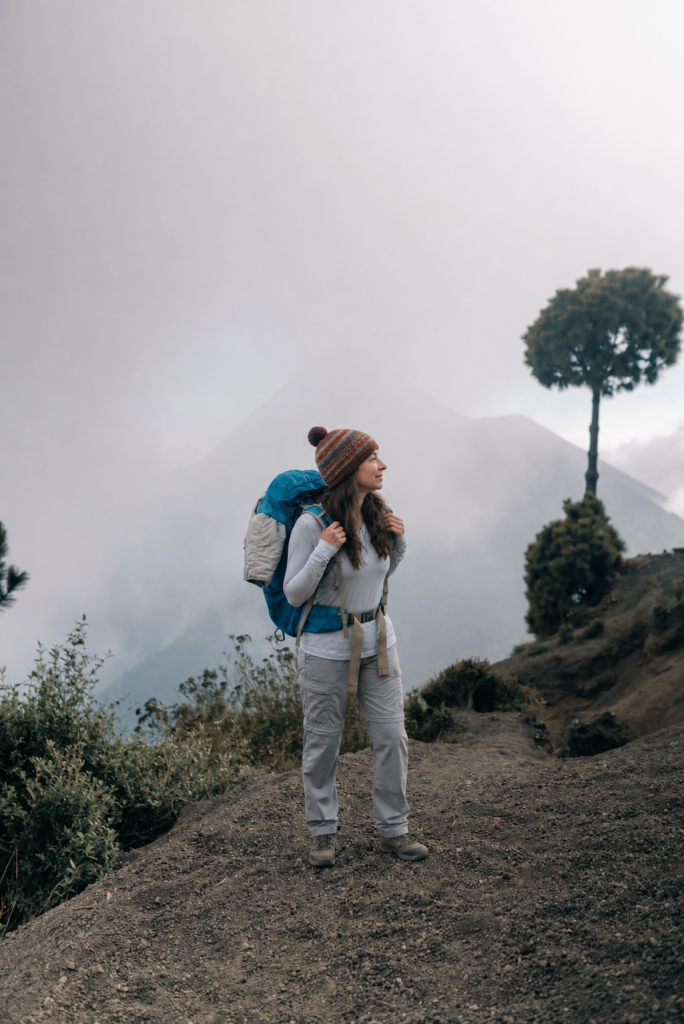 Solo female hiker pausing on the Acatenango volcano trail above the clouds