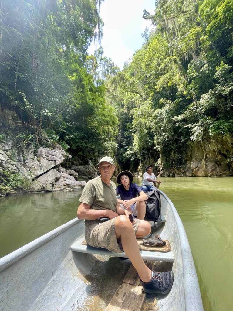 Visitors riding in a cayuco through El Boquerón Guatemala canyon with a local boatman paddling behind them.