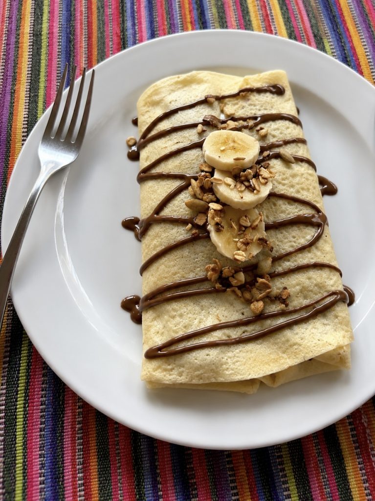 Gluten-free crepe with chocolate drizzle, banana, and granola at Fernando's Kaffee Antigua Guatemala