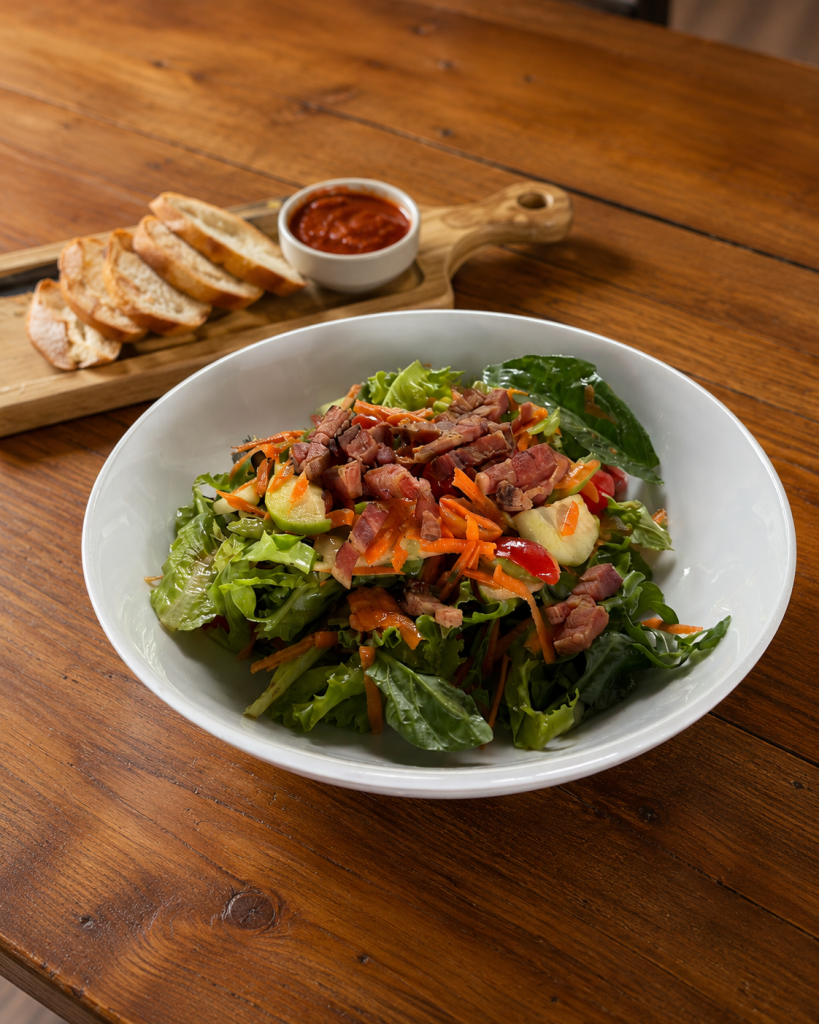 Gluten-free salad with grilled meat, vegetables, and gluten-free bread on the side