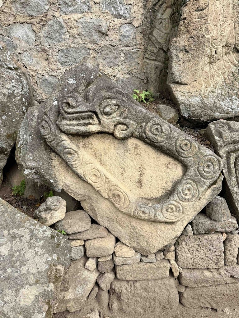 Trapezoidal carved stone with spiral and animal-like motifs at Chuitinamit near Santiago Atitlán.