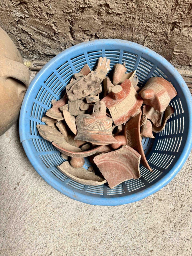 Fragments of decorated pottery and ceramic vessels displayed in a plastic basket at Chuitinamit near Santiago Atitlán.
