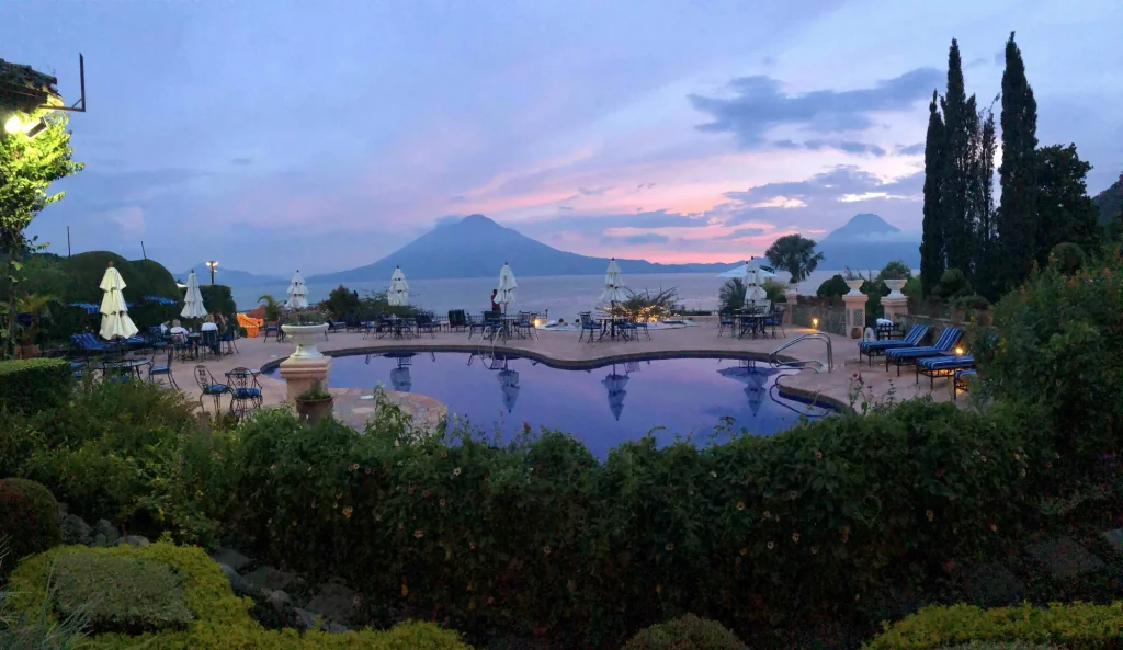 Restaurant terrace and pool at Hotel Atitlán during sunset with volcano views across Lake Atitlán