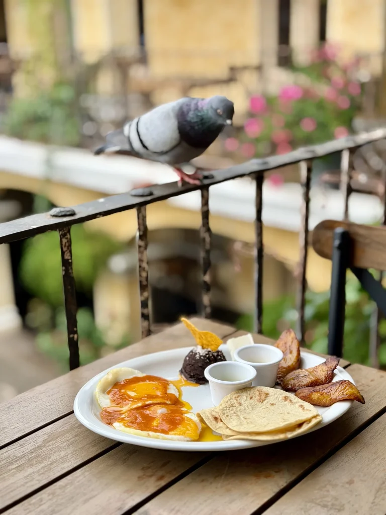 Guatemalan breakfast with eggs, black beans, fried plantains and corn tortillas on a balcony at Casa Realeza.