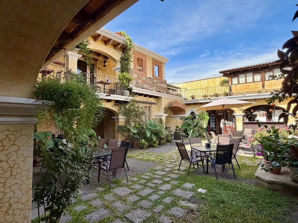 Colonial courtyard with garden seating and yellow archways at Hotel Casa Realeza in Antigua Guatemala.