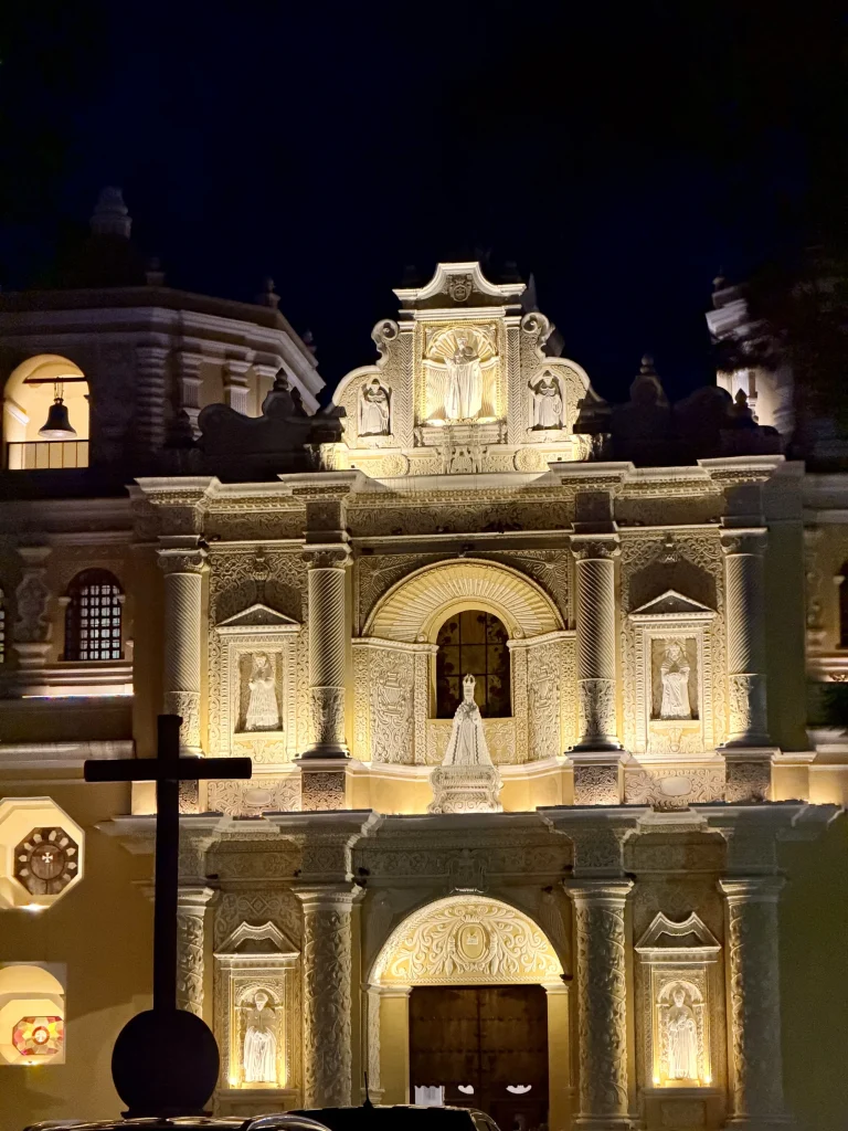 Illuminated yellow façade of La Merced Church in Antigua Guatemala at night.