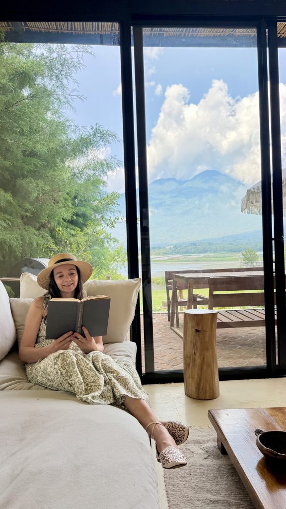 Reading beside floor-to-ceiling Lake Atitlán views inside Casa Teo Airbnb near Santiago Atitlán Guatemala
