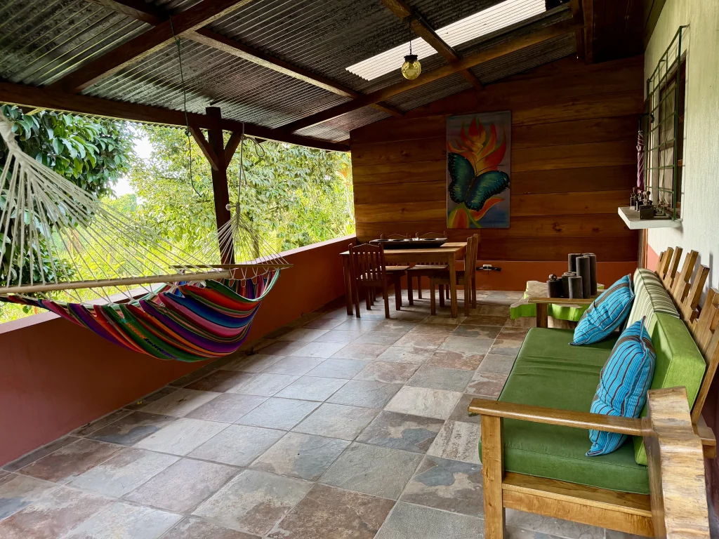 Covered private terrace with hammock, sofa and dining table outside a room at Patrocinio Lodge in Guatemala