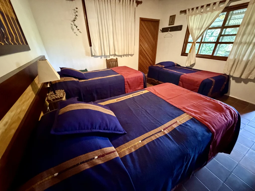 Three-bed guest room with Guatemalan textiles at Patrocinio Lodge inside Reserva Patrocinio Guatemala